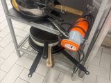 several pans and pans sit on a metal shelf in a kitchen