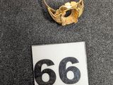 un gros plan d'une bague en or posée sur une table, à côté du chiffre 66