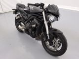 une moto noire garée dans une pièce aux murs blancs