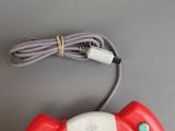 a red and white nintendo wii game controller with a cord