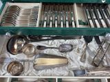 a green tray with silverware in it on a table
