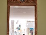un miroir accroché au mur au-dessus d'une table sur laquelle se trouve un vase