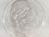 un bol en verre rempli d'eau posé sur une surface blanche