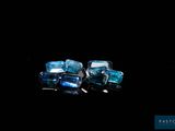 two pieces of blue topazte sit on a black surface