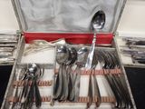 silverware in a silver case on a table with a red cloth