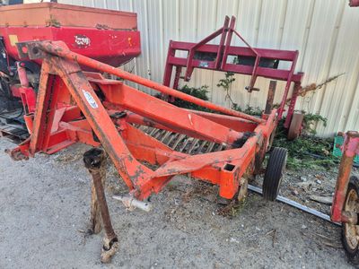un tracteur rouge garé sur la terre battue