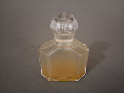 une petite bouteille en verre avec un bouchon transparent, posée sur une table