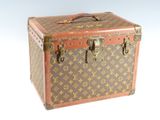 une valise marron et beige posée sur une surface blanche