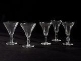 six empty wine glasses lined up in a row on a black surface