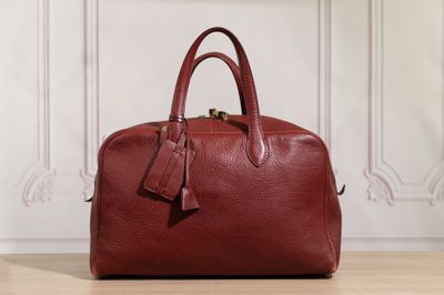 a red leather handbag sitting on top of a wooden floor
