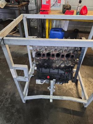 une photo représentant un moteur de voiture posé sur un chariot dans un garage