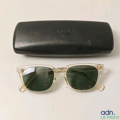 une paire de lunettes de soleil et son étui posés sur une table, à côté d'une paire de lunettes