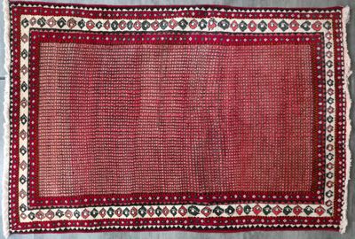 un tapis rouge à motifs posé sur un sol gris