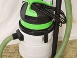un aspirateur vert et blanc et un tuyau vert posés par terre