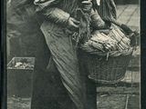 une vieille photo en noir et blanc représentant une femme tenant un panier rempli de poissons