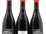 trois bouteilles de vin posées les unes à côté des autres sur une surface blanche