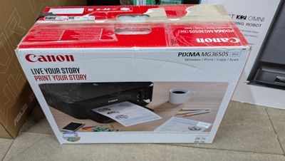 a canon printer sitting on top of a box on the floor