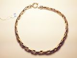 a close up of a gold chain bracelet on a white surface