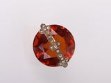 un gros plan sur une broche en pierre rouge et diamants