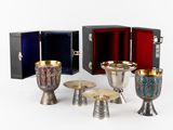 plusieurs gobelets, tasses et plateaux en argent et en or posés sur une surface blanche