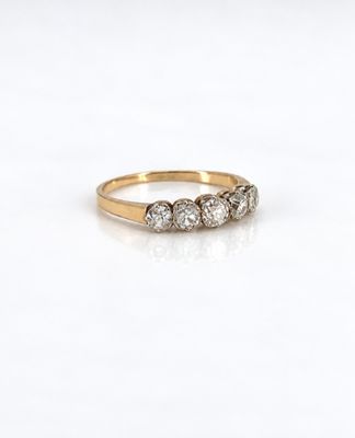une photo d'une bague en diamant à trois pierres posée sur une surface blanche