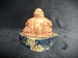 a statue of a man sitting on a blue and white bowl