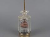 a small glass jar with a wooden top and a metal handle