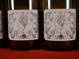 four bottles of wine are lined up on a red surface
