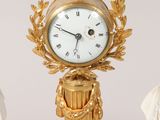 a gold clock sitting on top of a marble pedestal