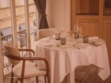 a table with a white table cloth on it and a chair in front of a window