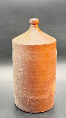 a brown jar with a wooden lid on a table