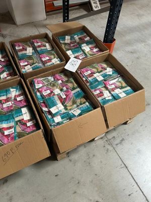 plusieurs cartons contenant des articles divers, posés à même le sol dans un entrepôt
