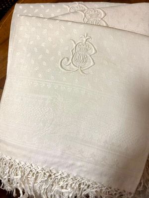 a white blanket with a monogram on it sitting on a table