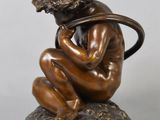an antique bronze statue of a boy with a hoop