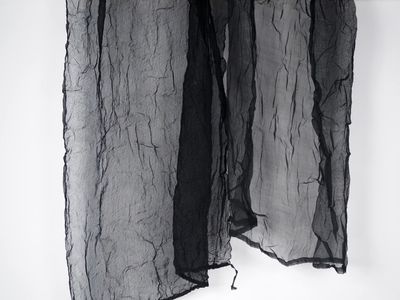 a black scarf hanging on a white wall