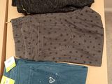 Trois paires de jeans pour homme se trouvent dans une boîte posée par terre.