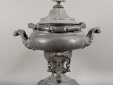 une théière ancienne en argent avec couvercle, posée sur un socle