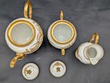 three pieces of porcelain tea set on a table with gold trimming