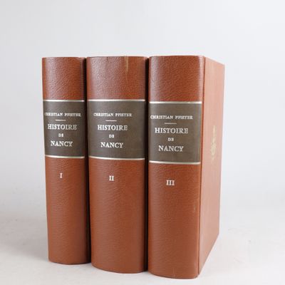three brown books sitting on top of each other on a white surface