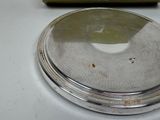 a silver plate on a white table with a box in the background