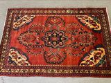 Le tapis posé au sol est rouge et présente un motif de fleurs et de feuilles.