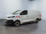 La camionnette blanche est garée dans une grande pièce au sol noir.
