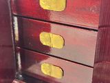 a small wooden chest of drawers with gold handles