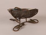 a small metal bowl with a leaf decoration on it