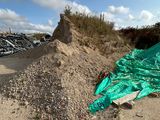une bâche verte posée par terre à côté d'un tas de gravats