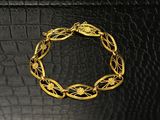 gros plan d'un bracelet en or sur une surface en cuir noir