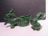 deux statues vertes représentant des lapins tirant une charrette sur laquelle se trouve un lapin