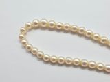 a close up of a white pearl necklace on a white surface