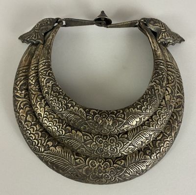 an antique silver necklace with birds on it on a white surface