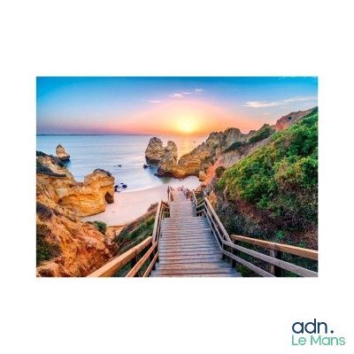 a wooden walkway going down to the beach at sunset